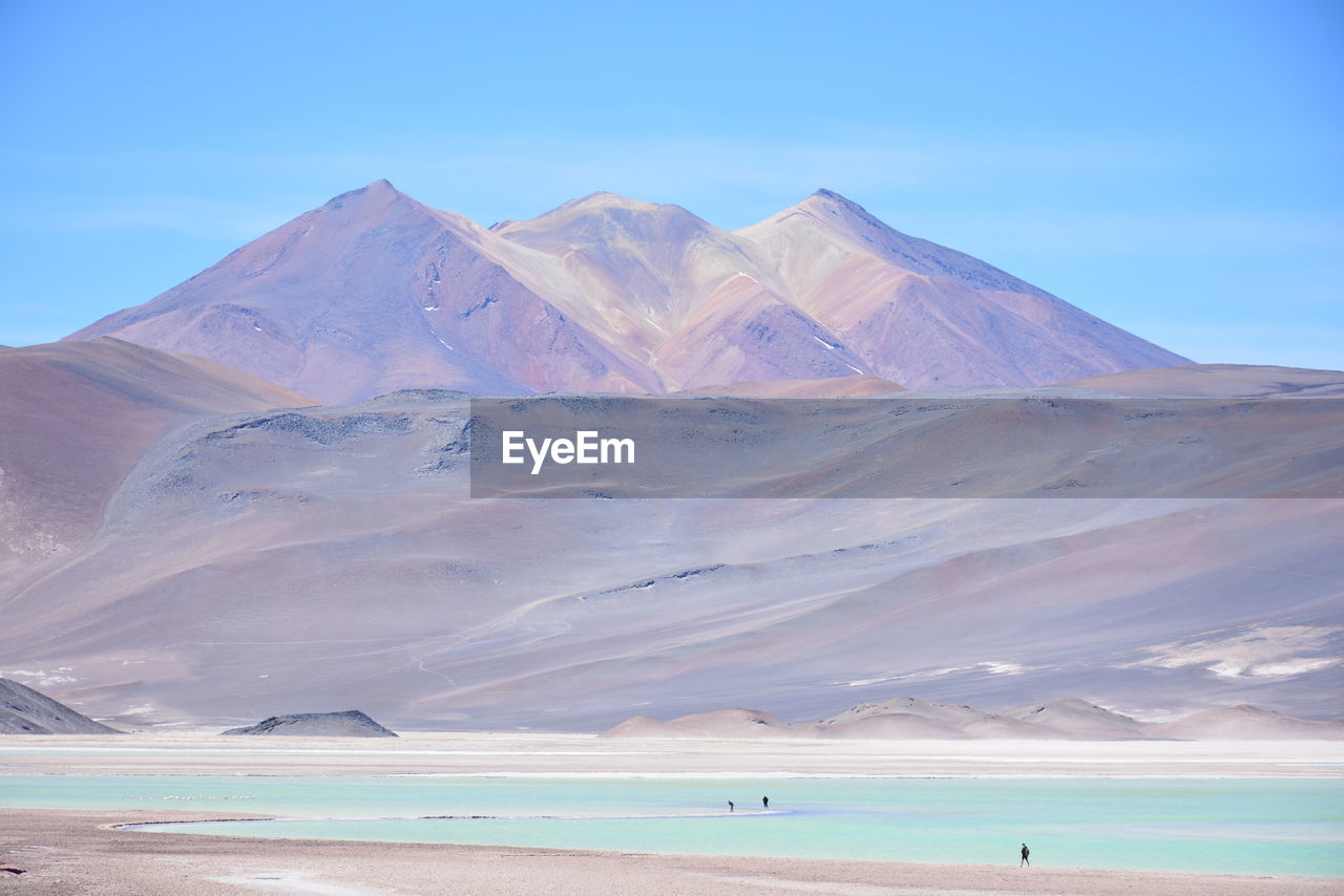 Scenic view of sea by mountains against sky