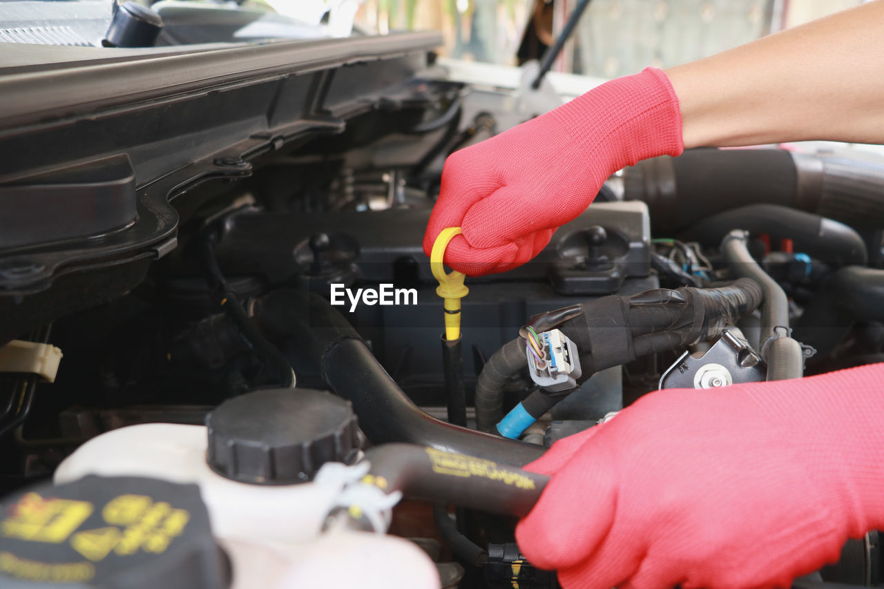 Cropped hand of mechanic repairing car engine