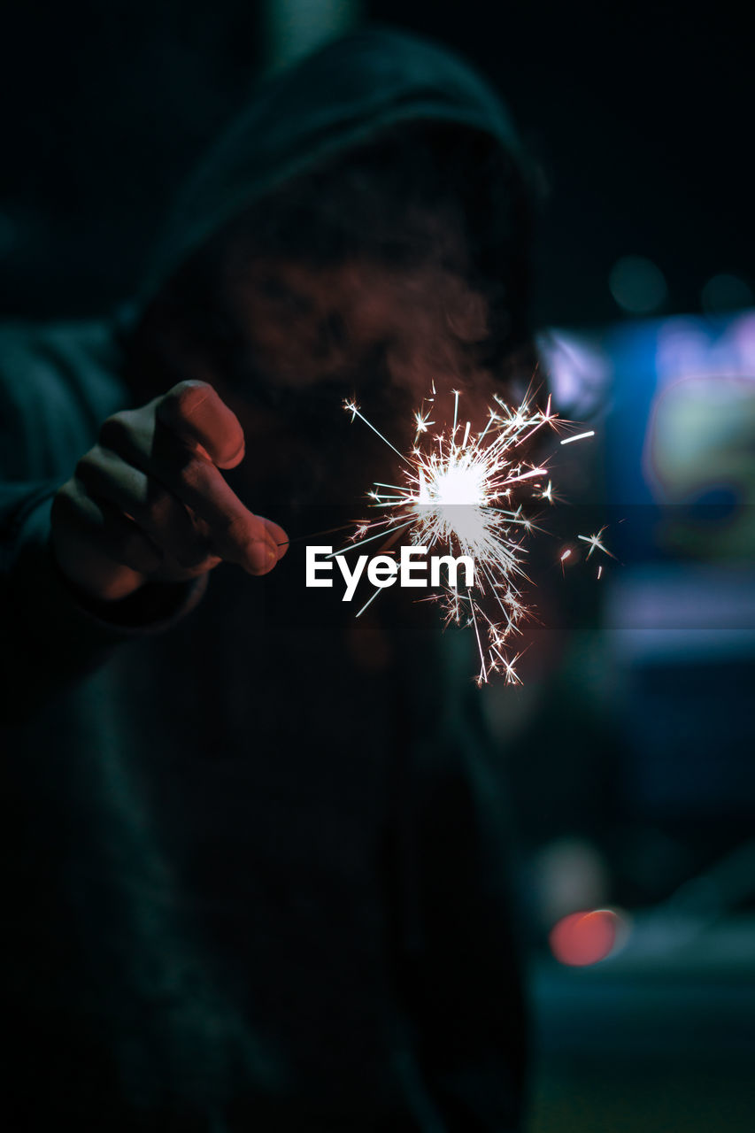 Man holding illuminated sparkler at night