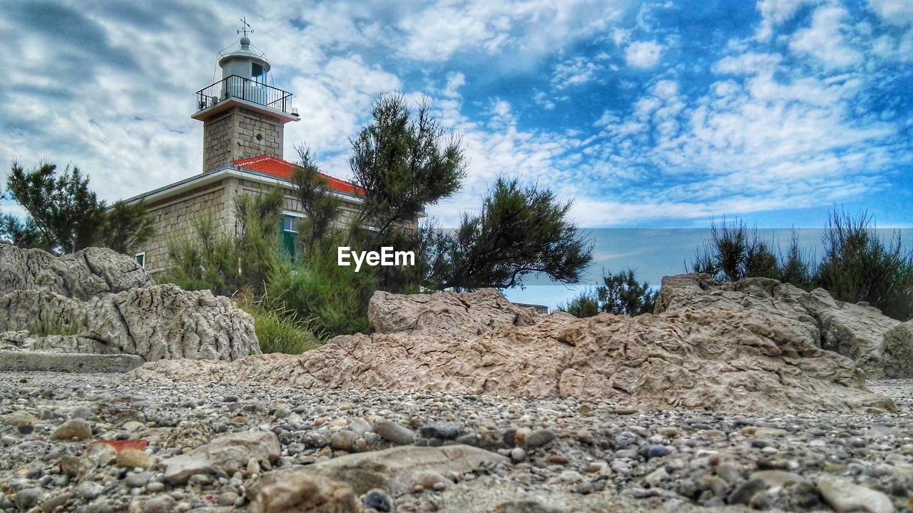 LOW ANGLE VIEW OF LIGHTHOUSE AGAINST CLOUDY SKY