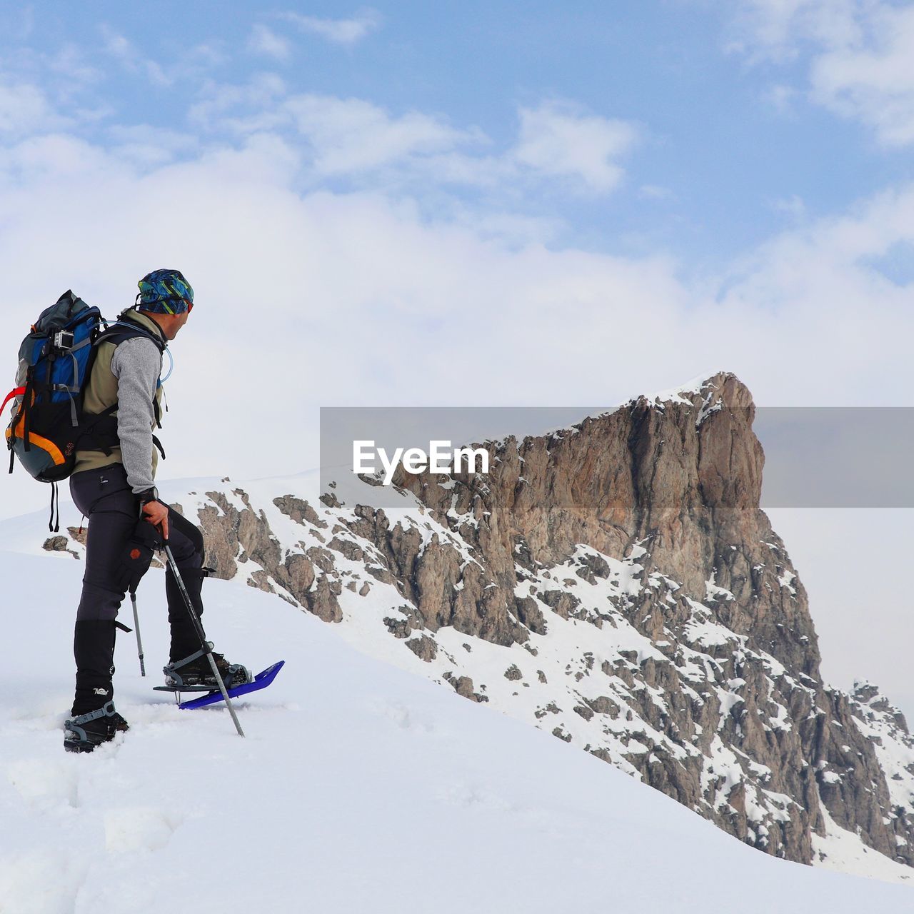 Full length of man hiking on snowcapped mountain against sky