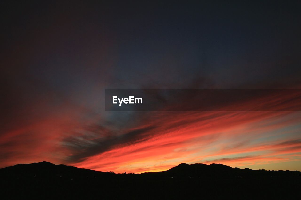 SILHOUETTE OF MOUNTAIN AGAINST DRAMATIC SKY