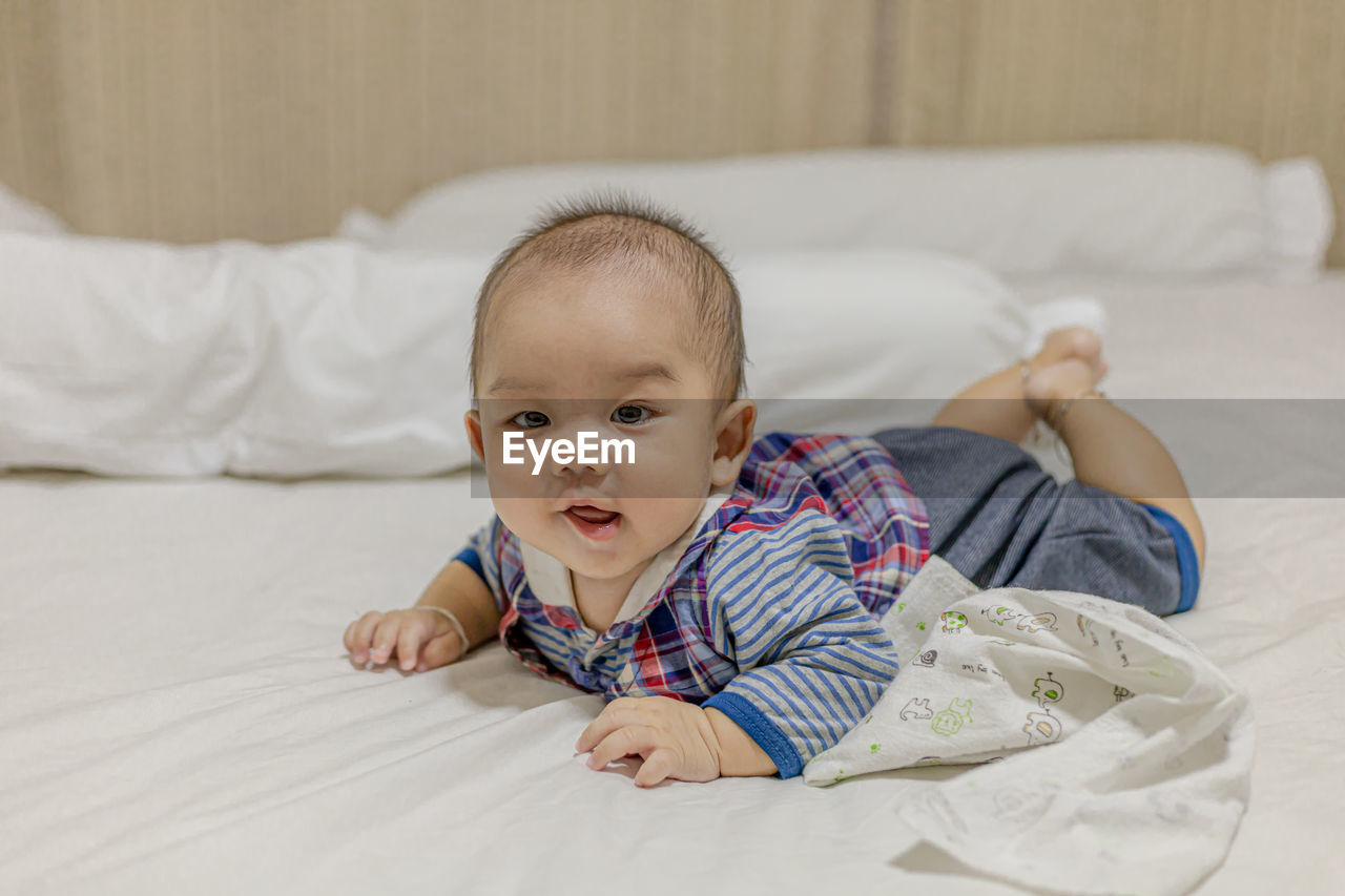 Portrait of cute boy lying on bed at home