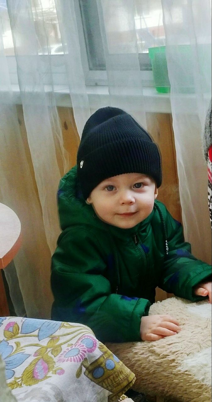 High angle portrait of baby boy standing by window at home