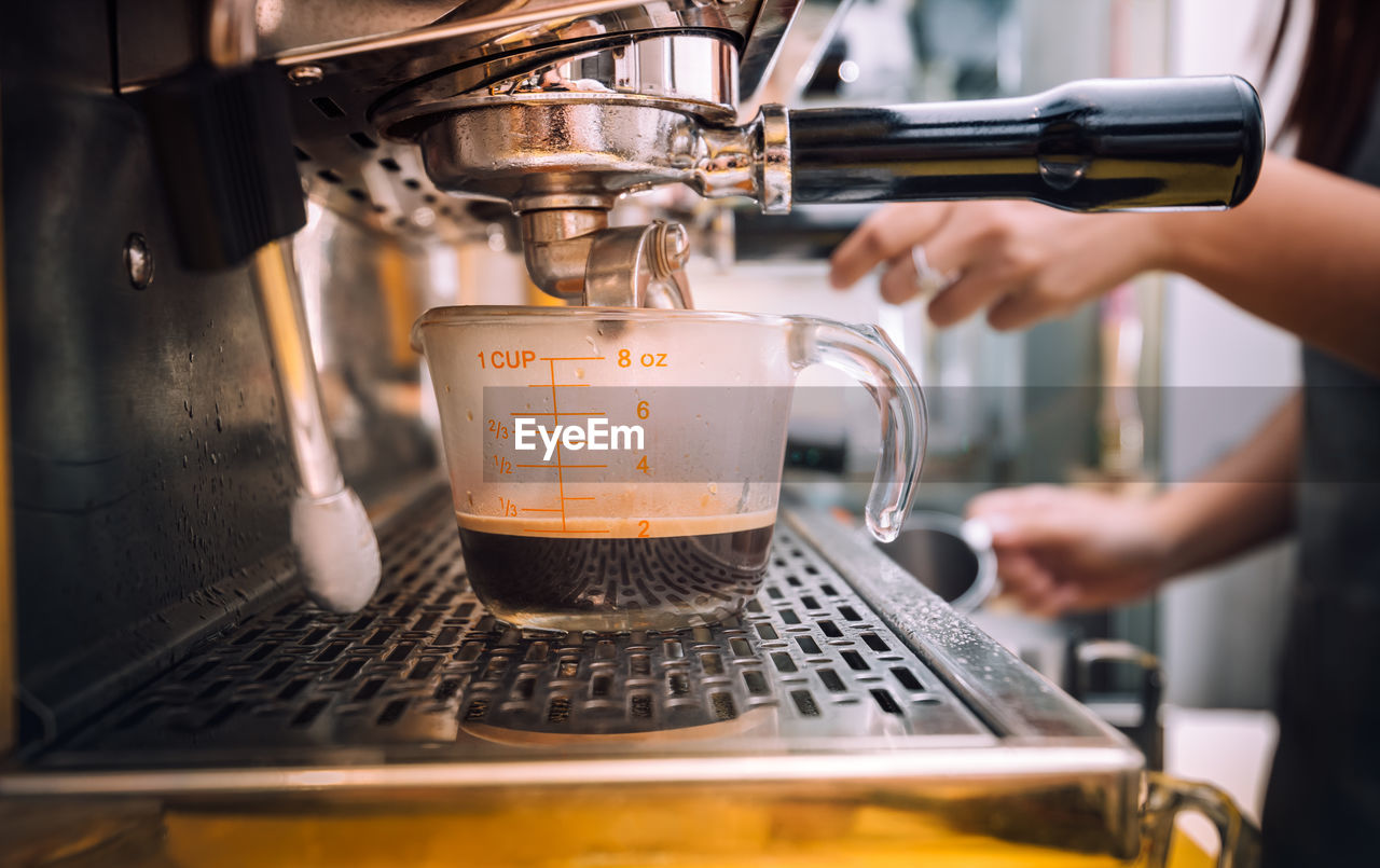 Midsection of barista preparing coffee at cafe