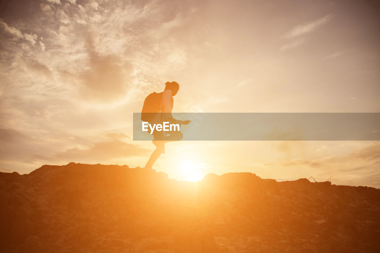 SILHOUETTE MAN STANDING ON MOUNTAIN AGAINST SUNSET SKY
