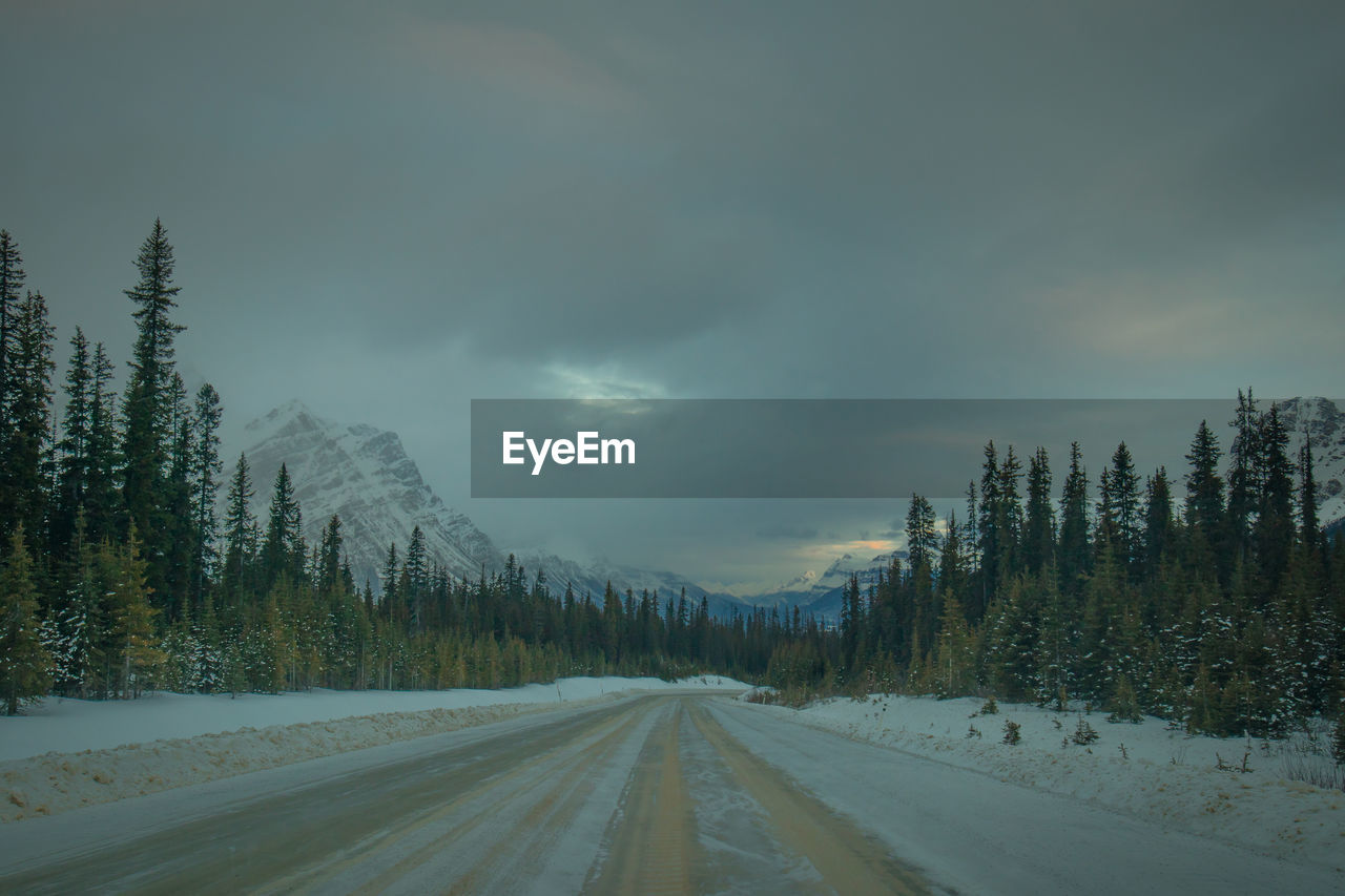 ROAD AMIDST SNOWCAPPED MOUNTAINS AGAINST SKY DURING WINTER