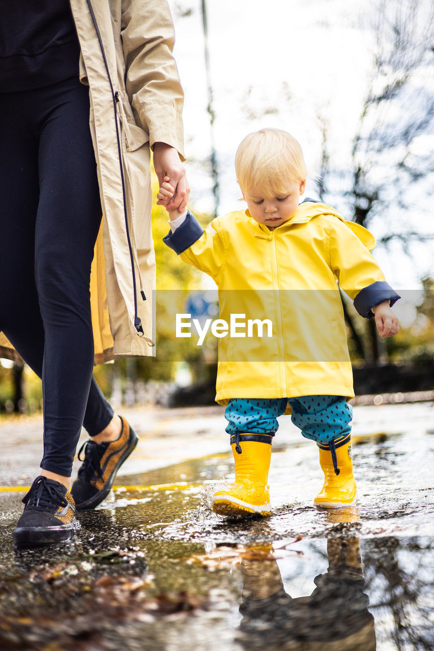 rear view of boy standing on puddle