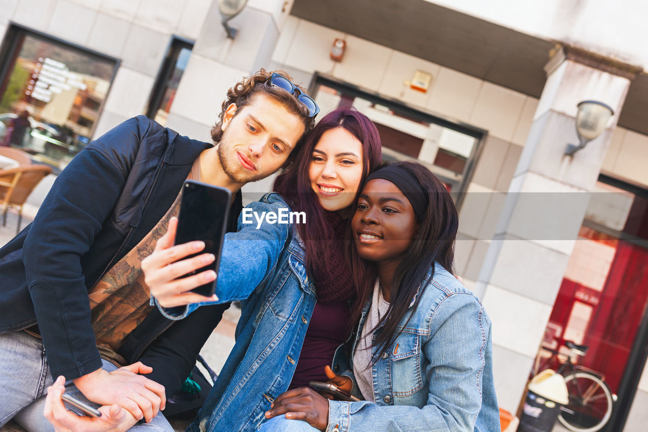 Multiracial friends taking selfie outdoors. happy friendship concept, students having fun together