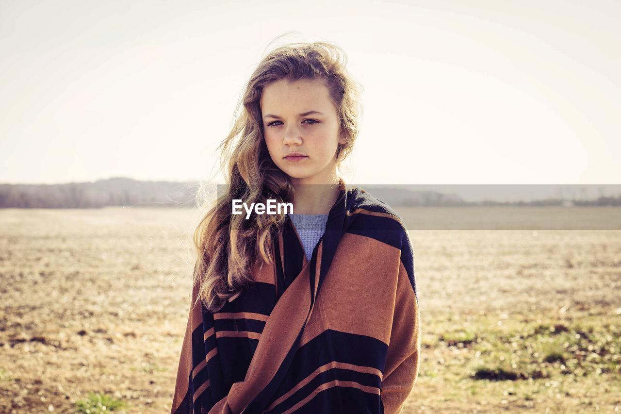 Portrait of girl standing on field against sky