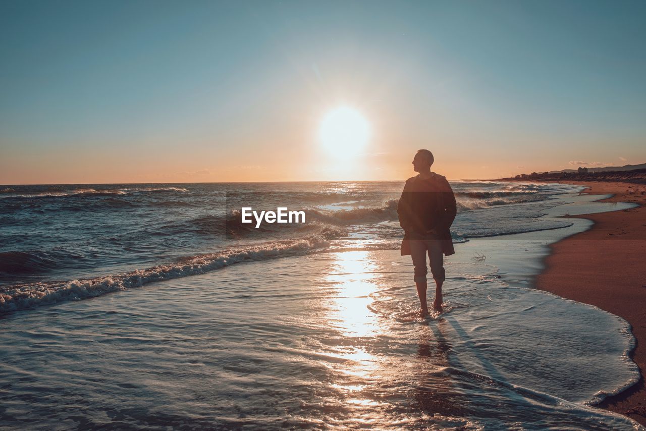 Man walking at beach during sunset