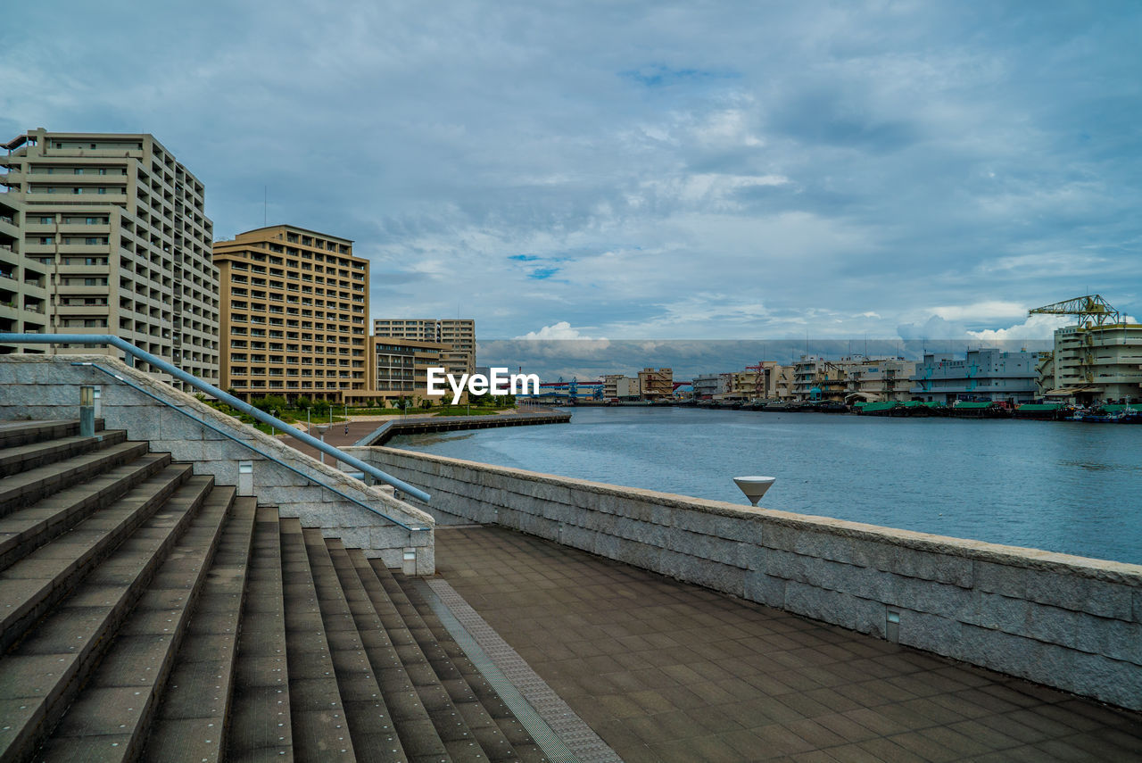 FOOTPATH BY RIVER AGAINST BUILDINGS IN CITY