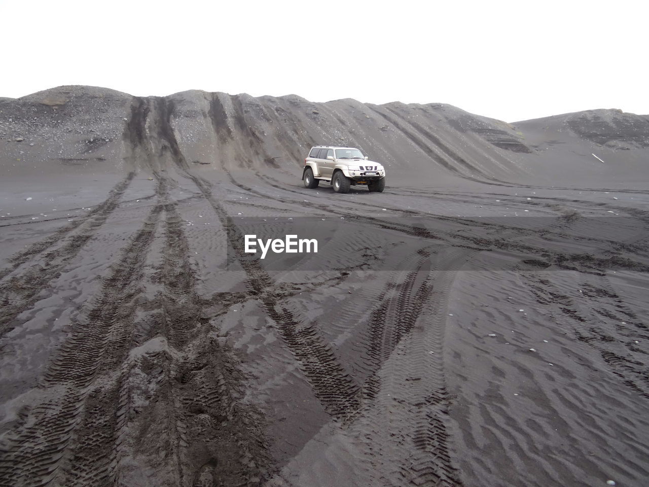 Off-road vehicle at desert against sky