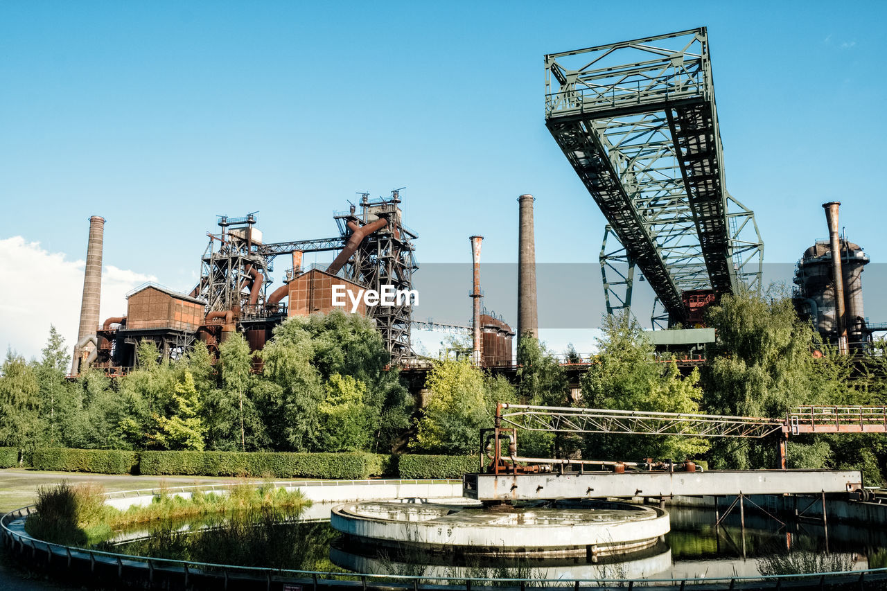 Industrial area by river against clear sky