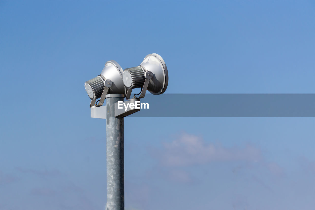 Low angle view of lighting equipment against blue sky