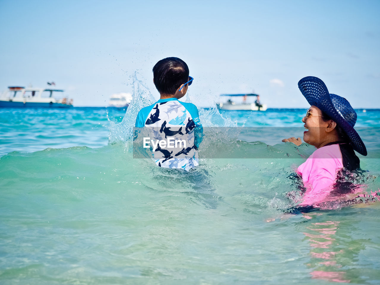 Mother and son swimming in sea against sky