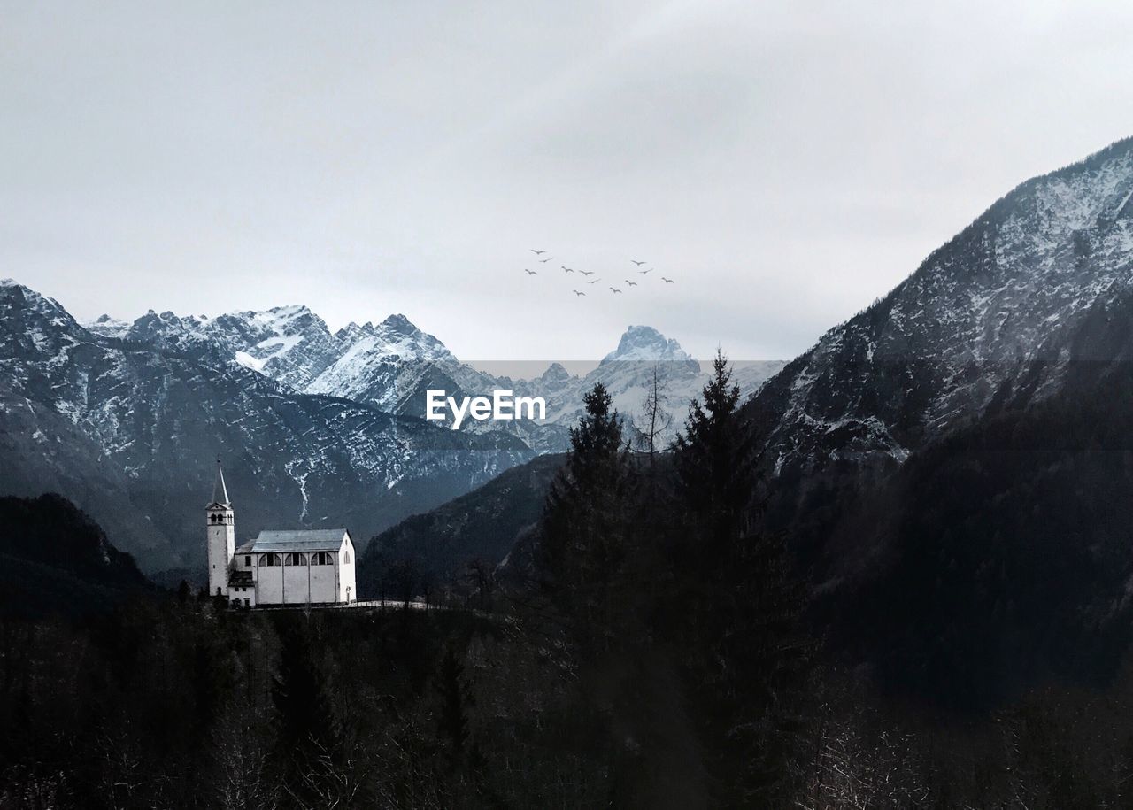 Distant view of historic church on mountain against sky during winter