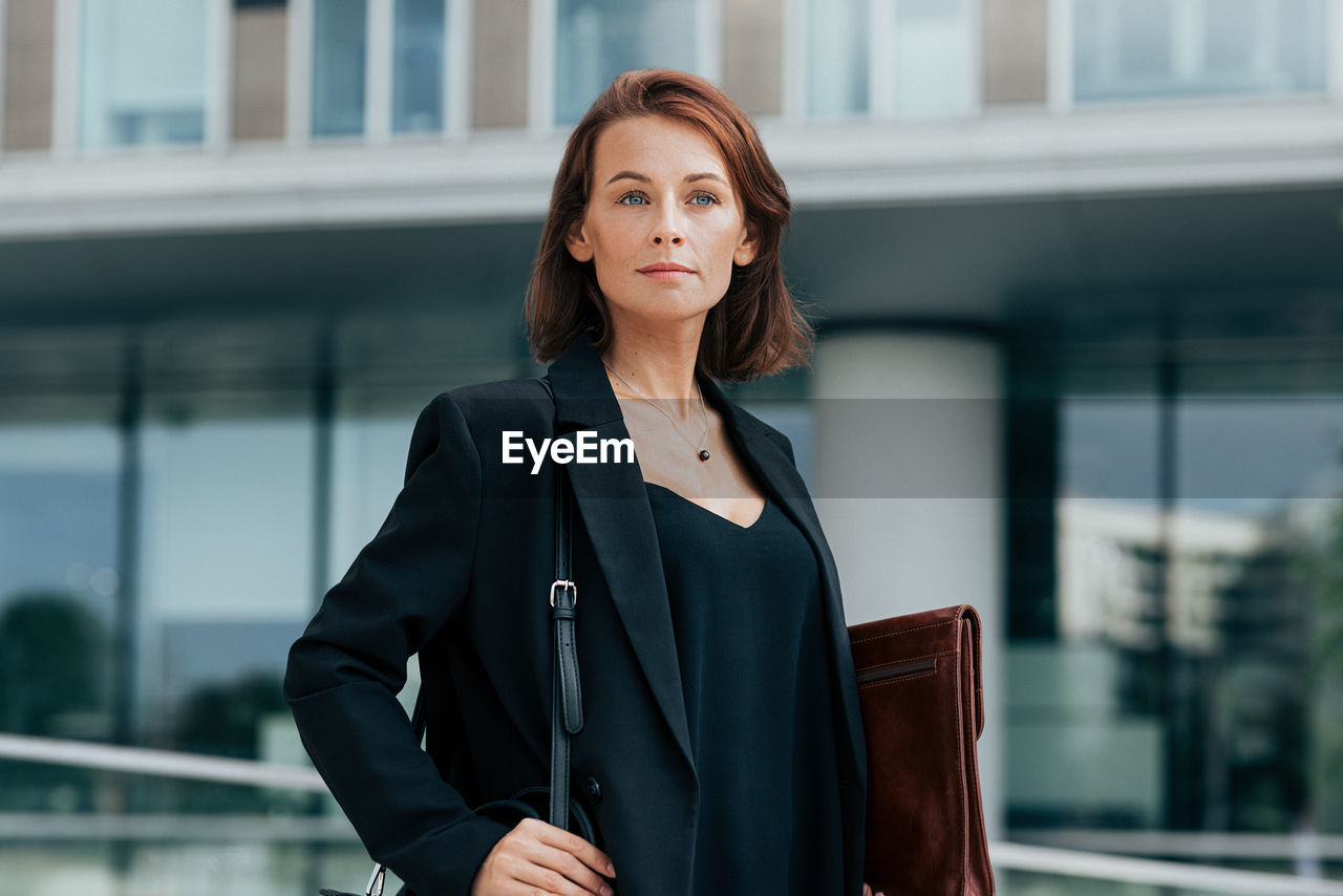 portrait of young businesswoman standing against building