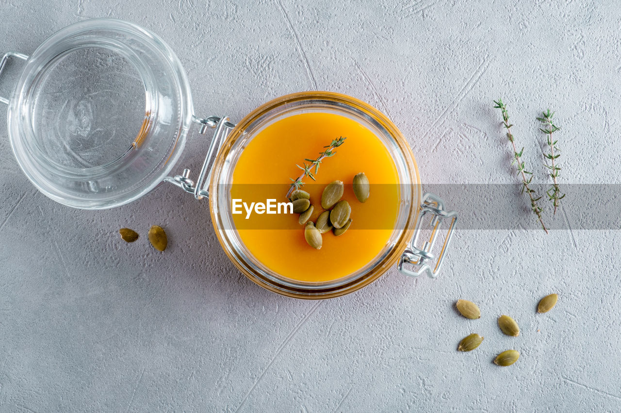 Pumpkin puree soup with pumpkin seeds and thyme in a glass jar. view from above.