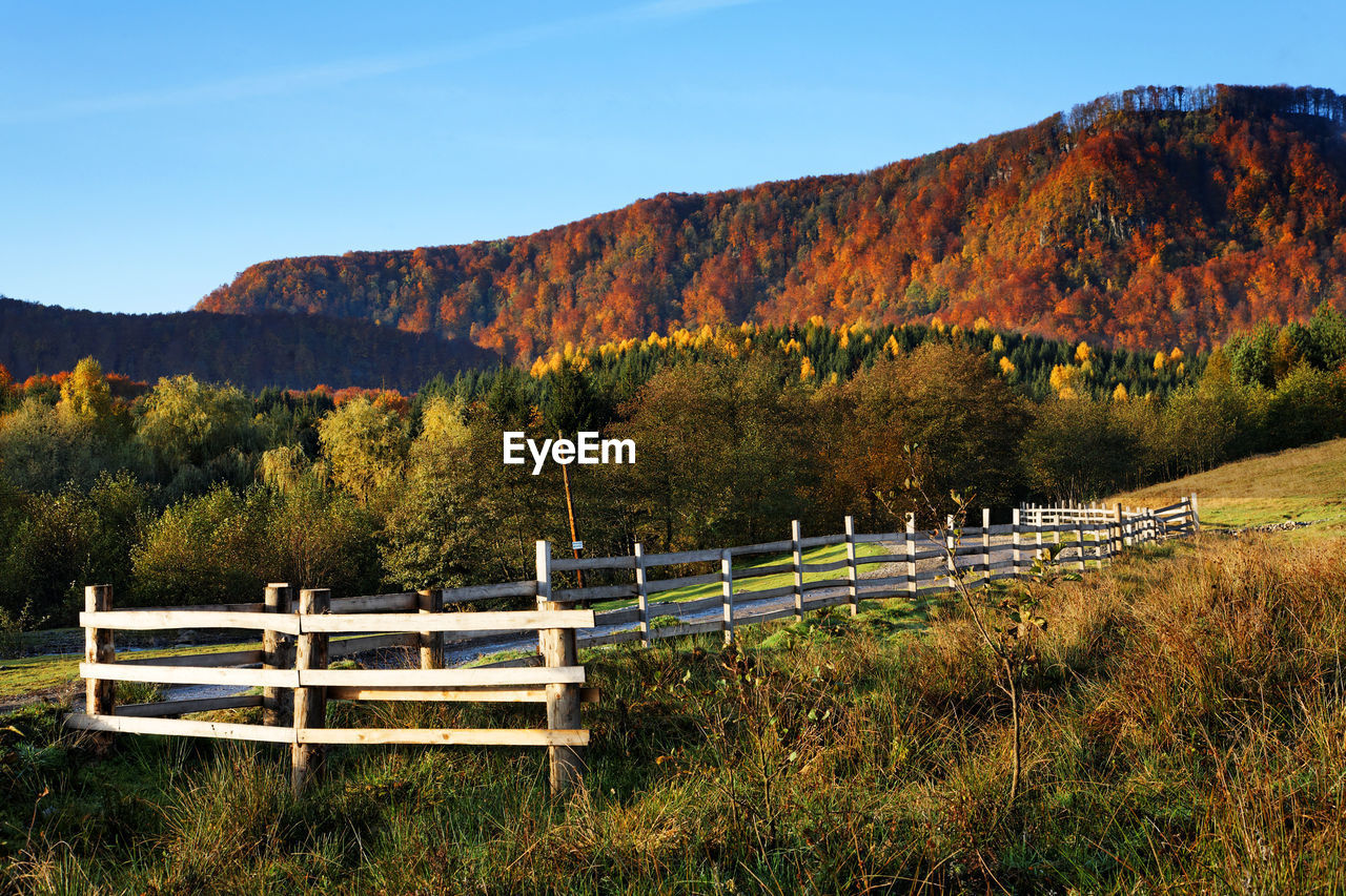 Scenic view of wooden fence against mountains in autumn