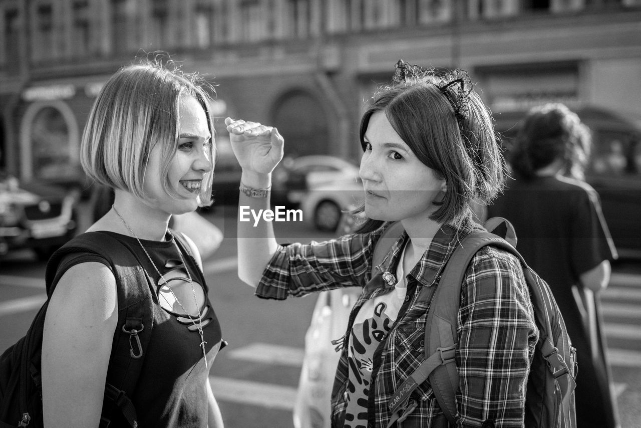 Female friends standing on road in city