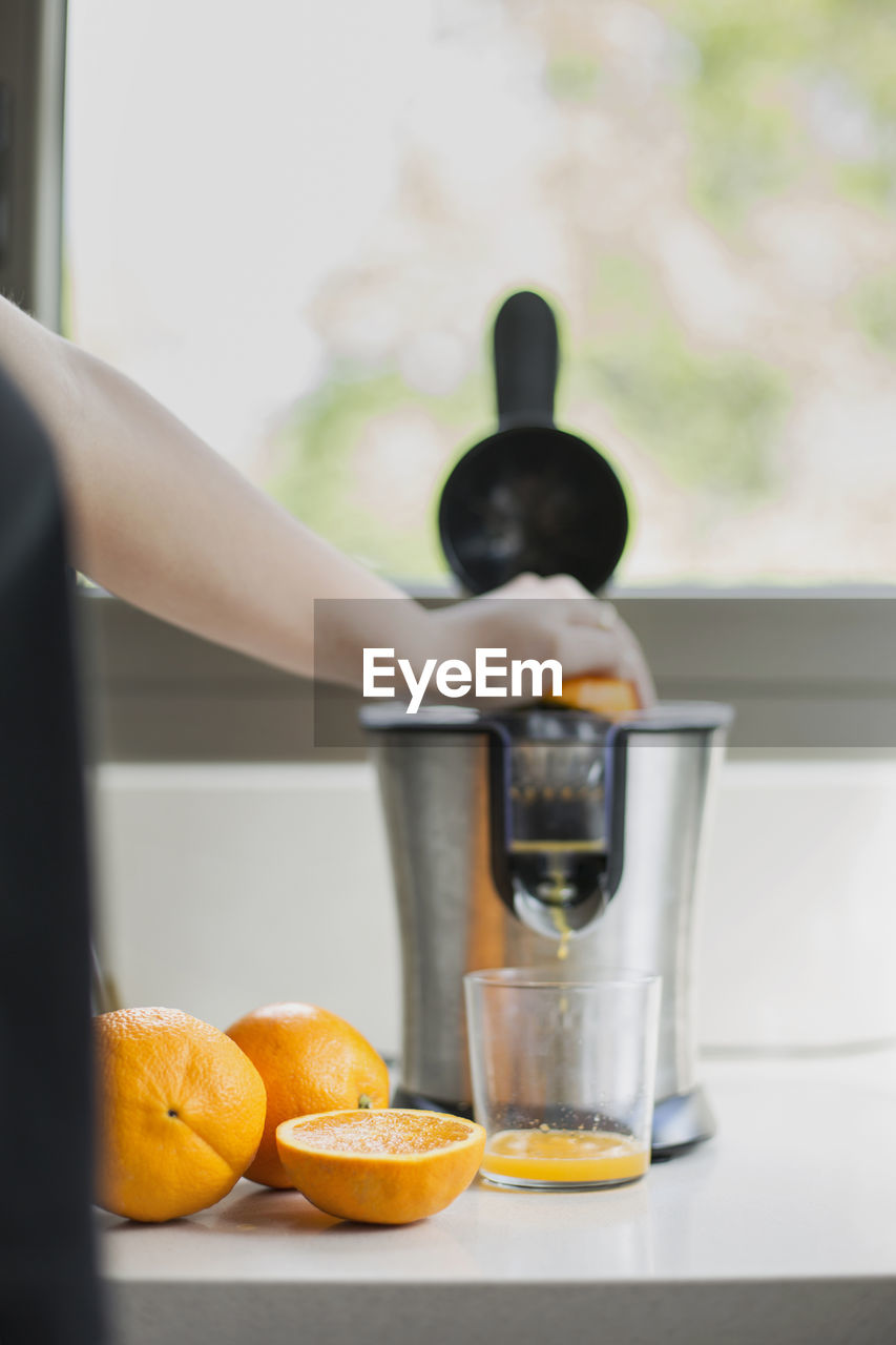 Midsection of man preparing orange juice on table