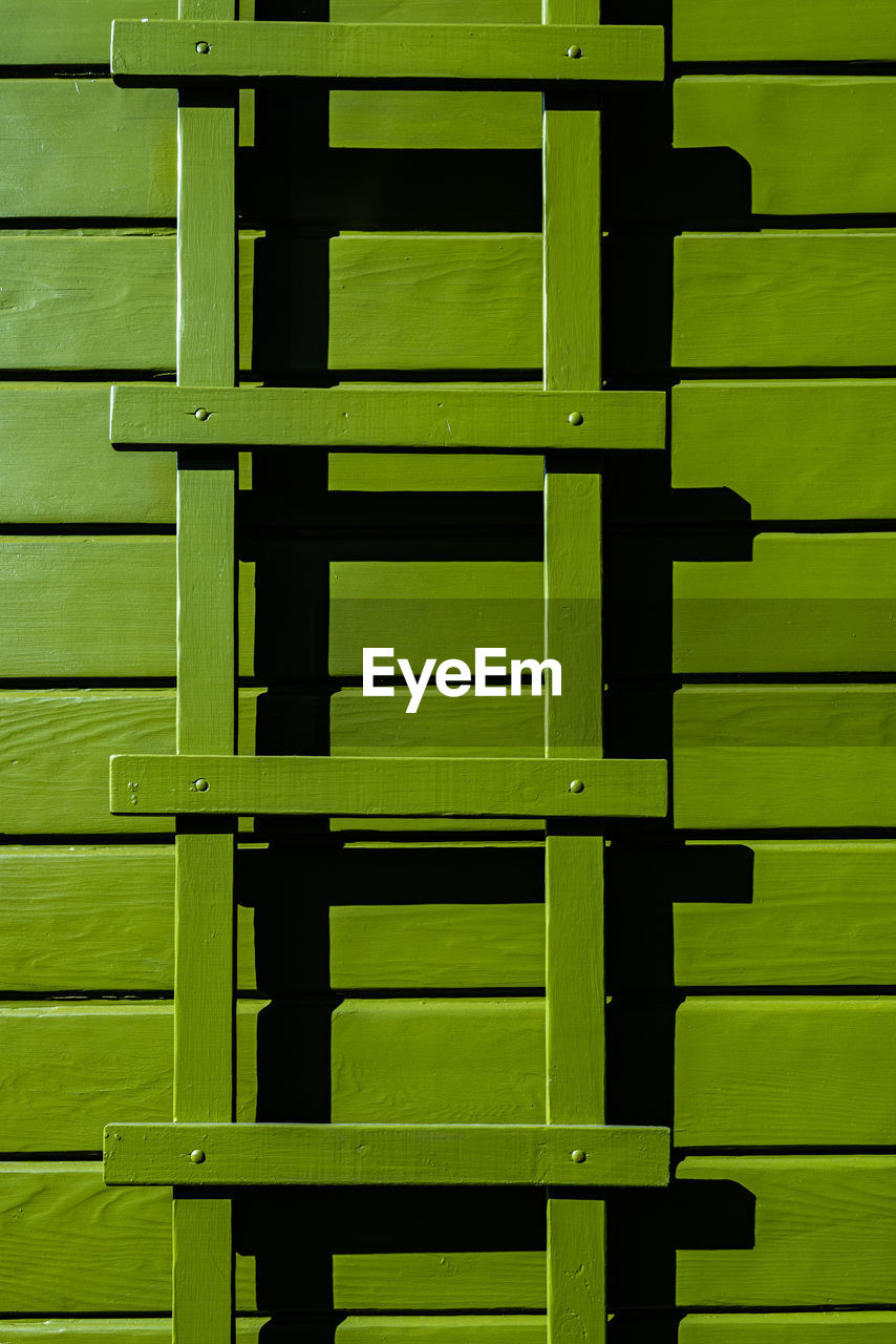 Avocado green color painted wood siding with matching trellis detail of home exterior 