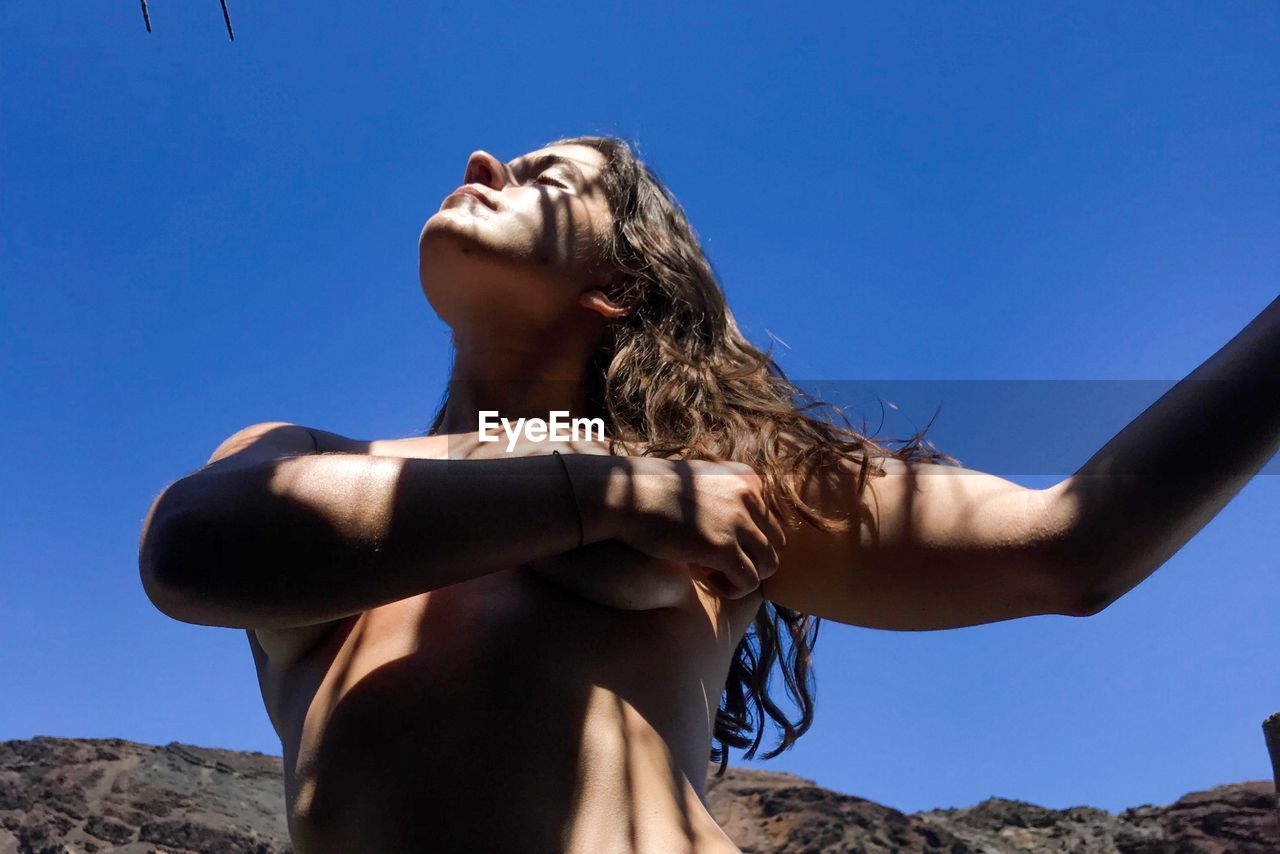 Low angle view of topless woman against clear sky