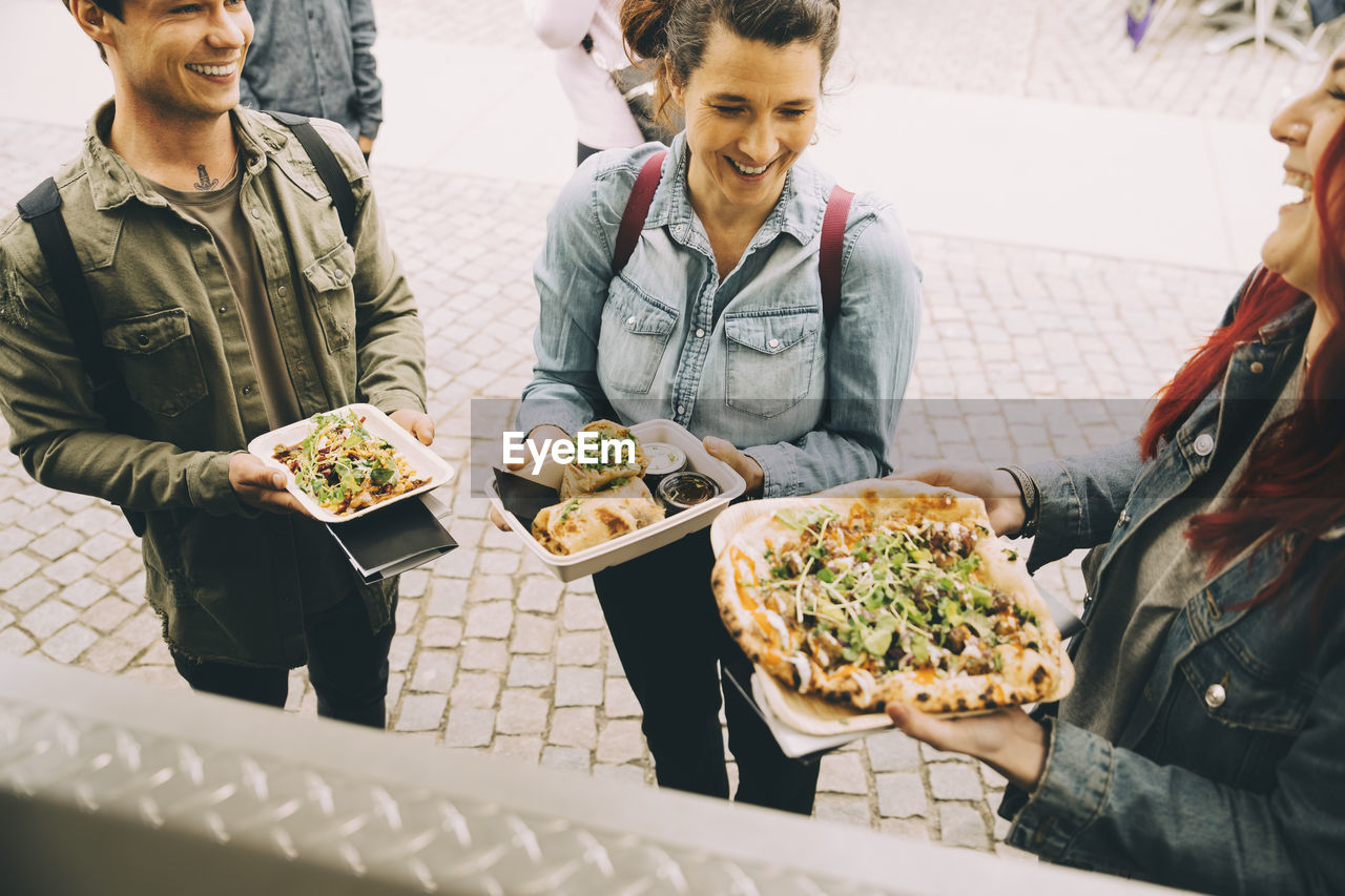 Male and female customers with food plate standing in city