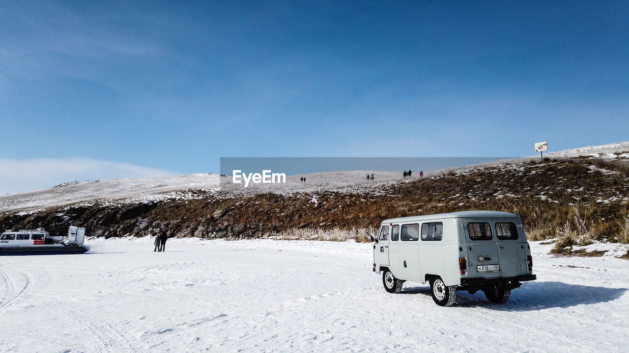 Car on snow covered mountain against blue sky