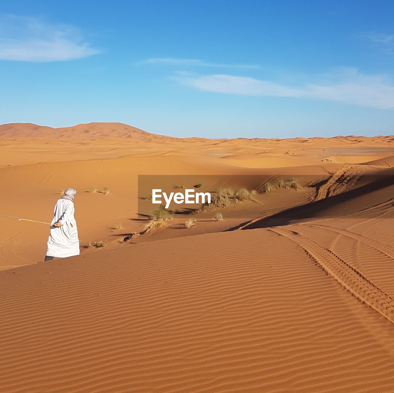 Rear view of man walking at desert against sky