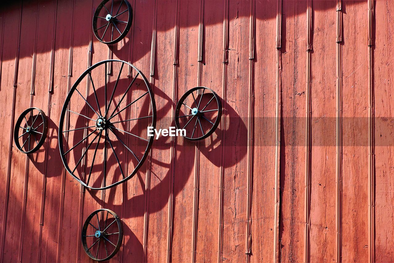 Antique wagon wheels mounted on side of red barn.