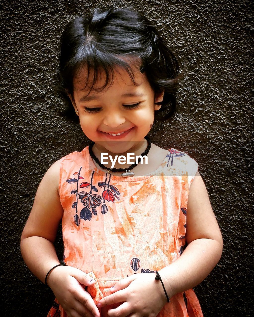 Portrait of cute girl smiling against wall