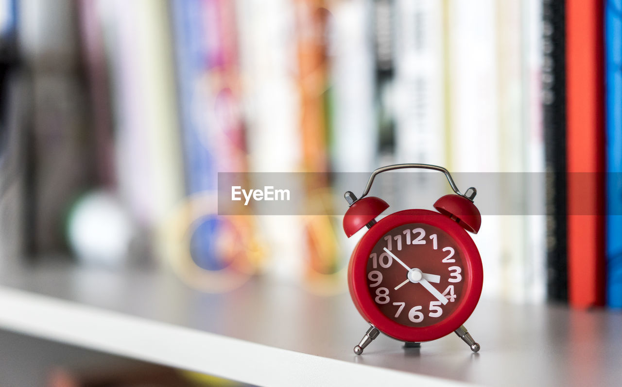 Close-up of alarm clock against books