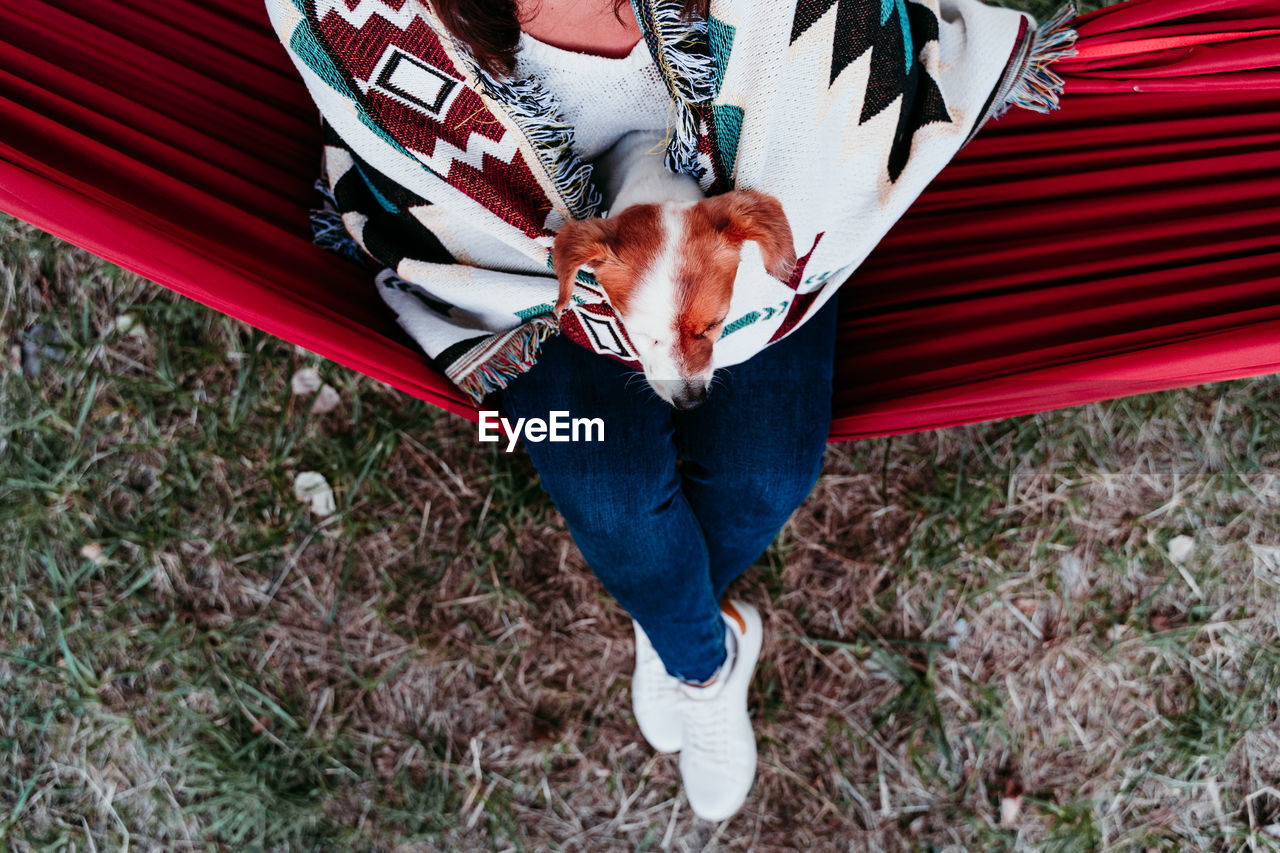 Low section of woman with dog sitting in hammock