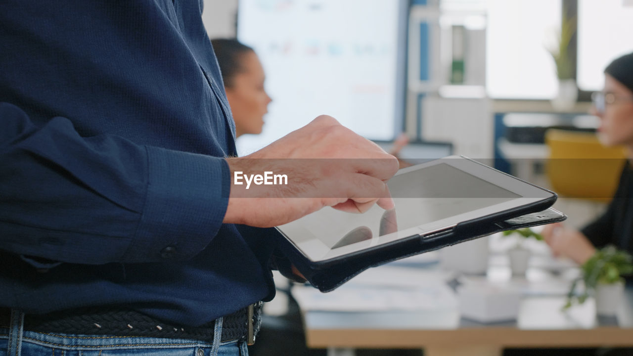 Midsection of businessman using digital tablet