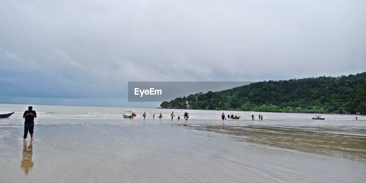 People at beach against sky