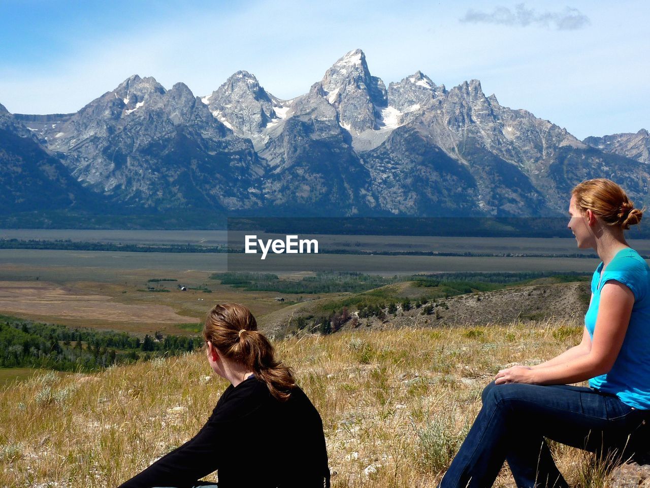 Women sitting on field against mountains