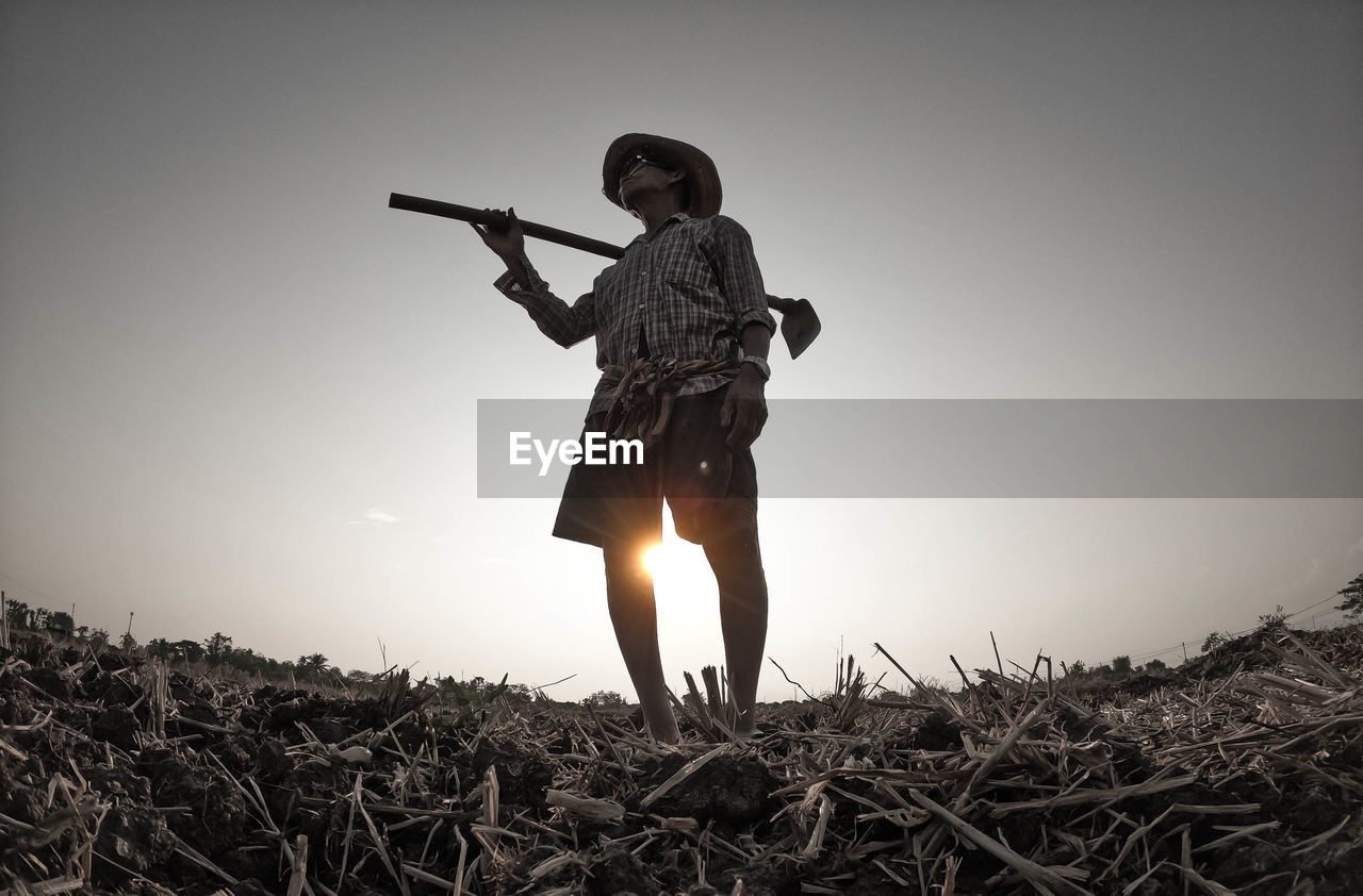 Man standing on field against clear sky during sunset