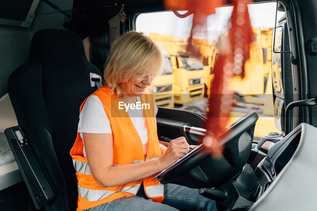 Smiling driver writing sitting in truck