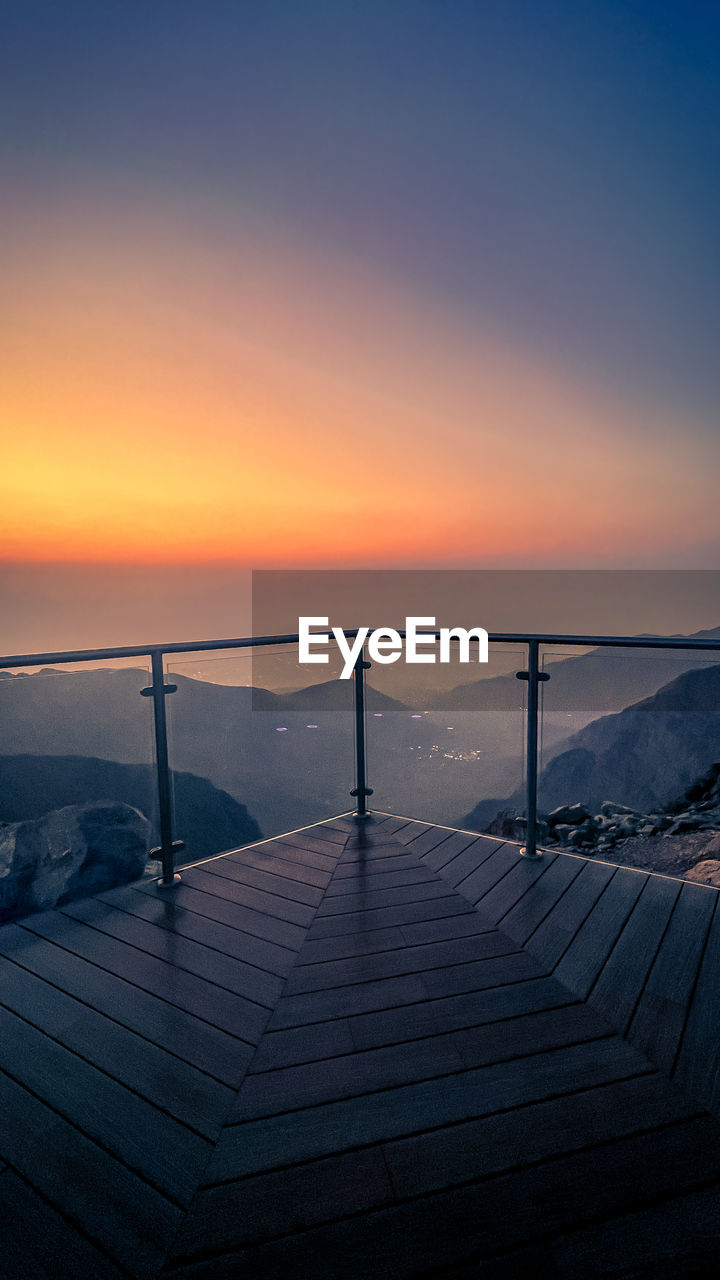 sky, sunset, horizon, sunlight, sea, dawn, beauty in nature, scenics - nature, water, nature, reflection, ocean, tranquility, architecture, tranquil scene, evening, no people, travel destinations, built structure, horizon over water, sun, cloud, travel, environment, outdoors, tourism, idyllic, railing, blue, landscape, land