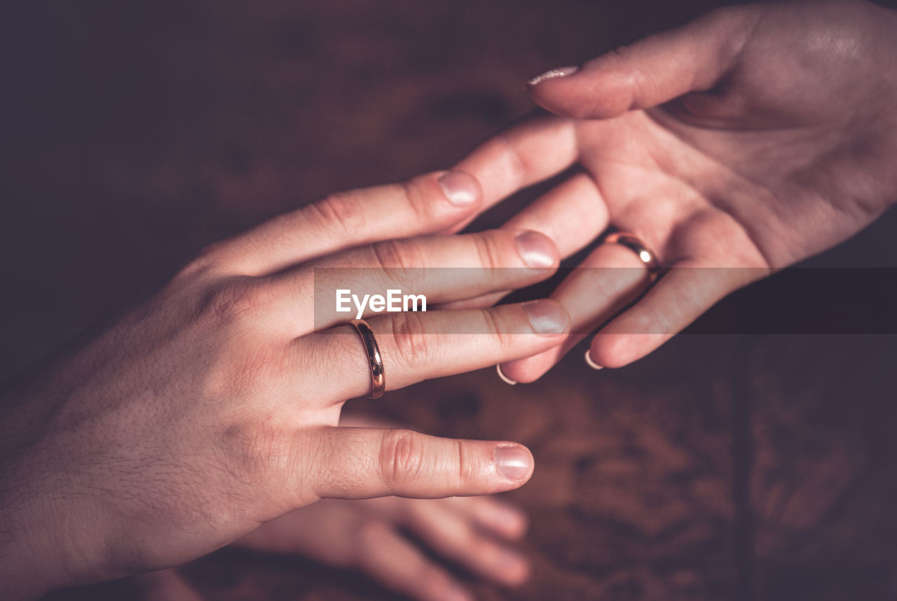 Close-up of couple with wedding rings holding hands