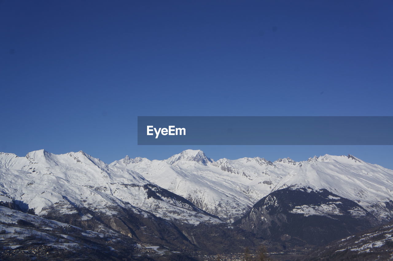 Scenic view of snowcapped mountains against clear blue sky