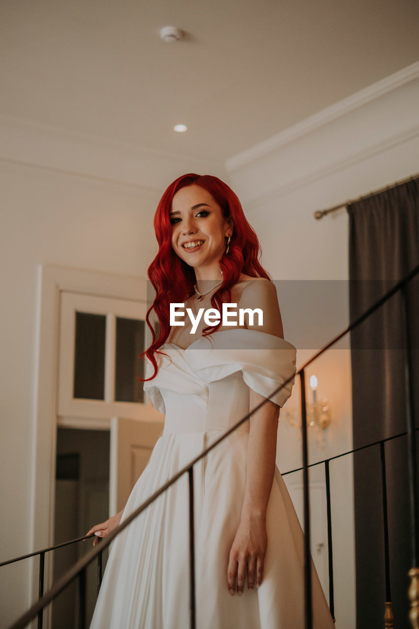 Red haired bride sitting in the armchair with bouquet