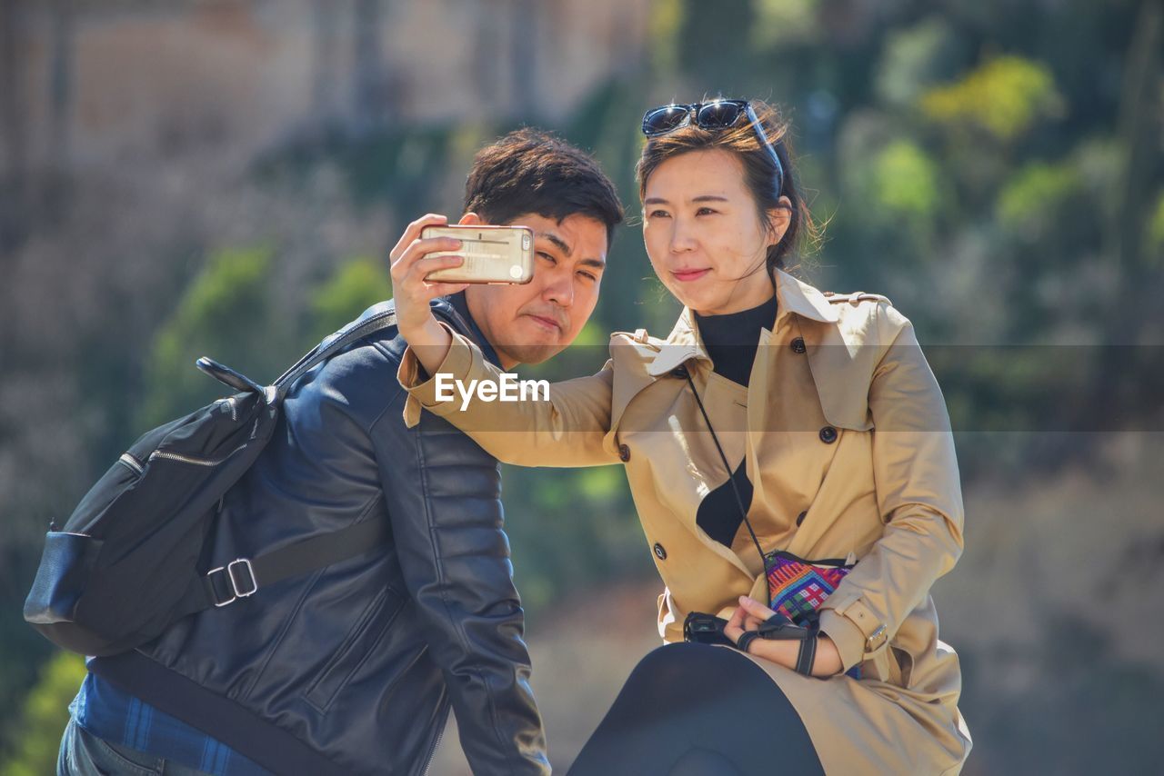 Young couple clicking selfie with smart phone outdoors