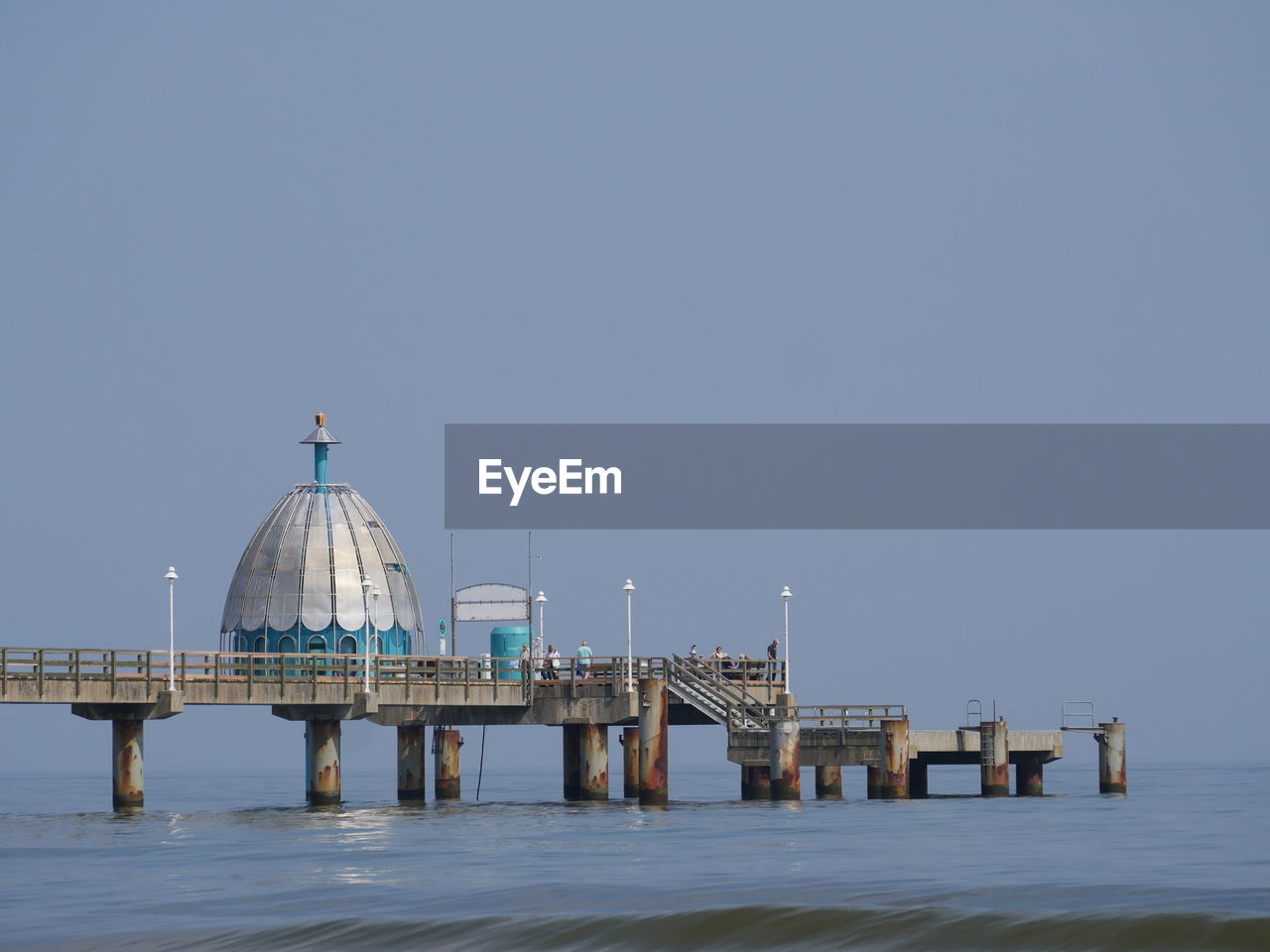 Pier over sea against clear blue sky