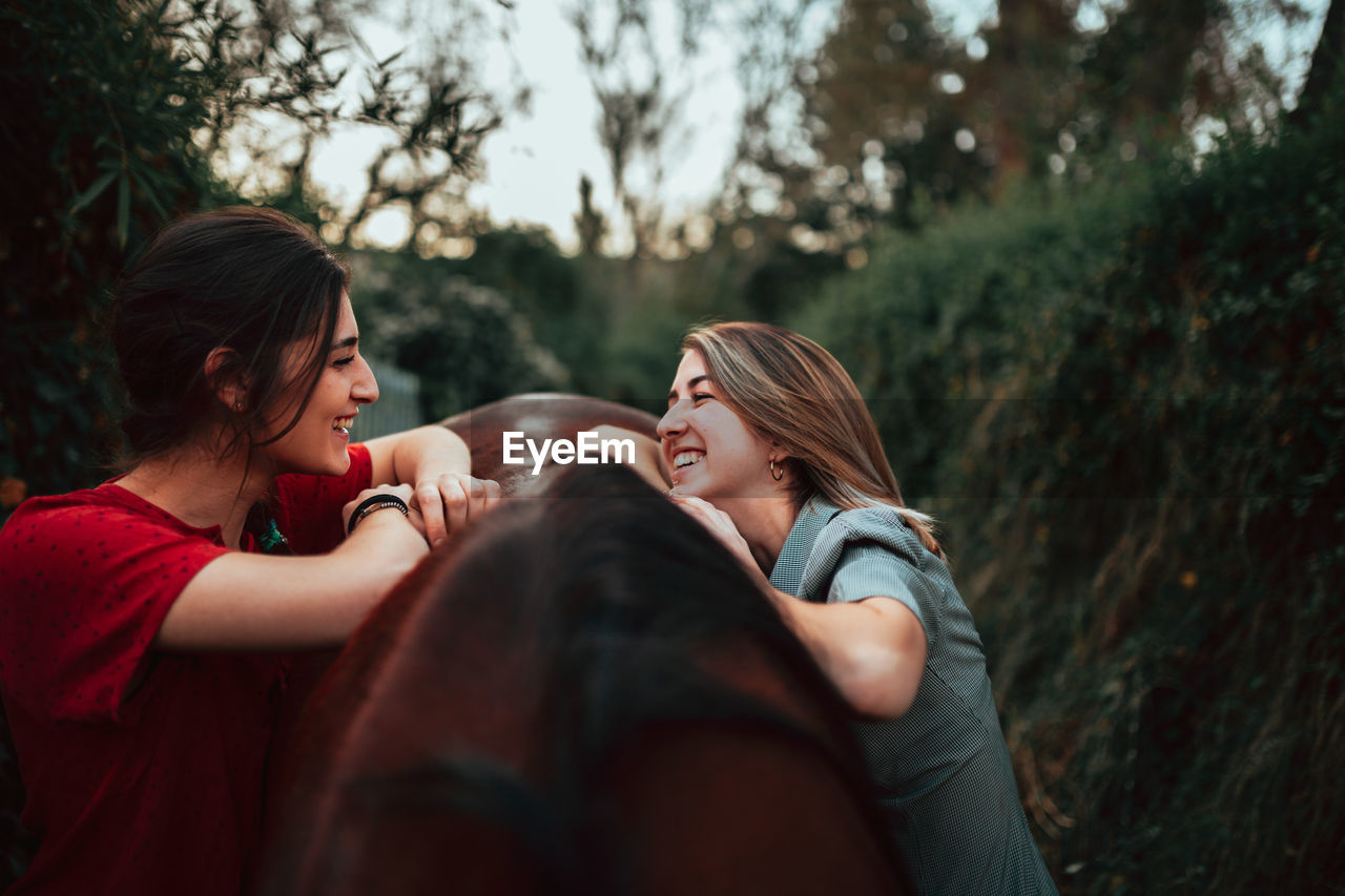 Smiling women with horse standing outdoors