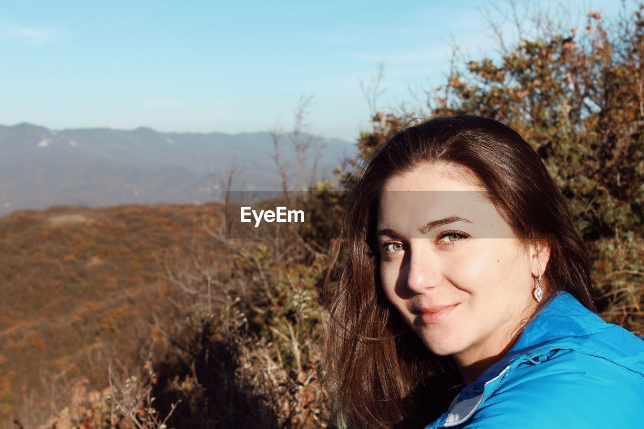 Portrait of smiling young woman against sky