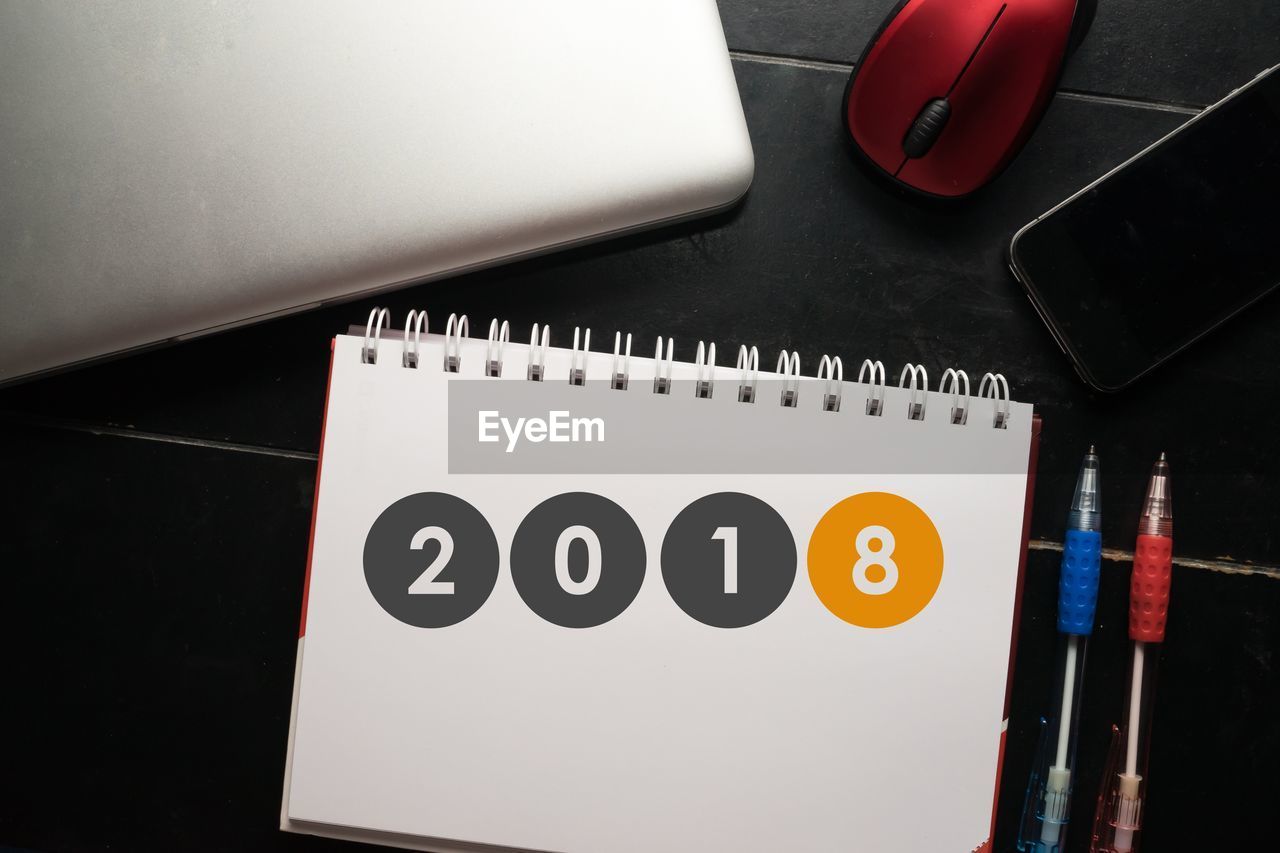 High angle view of calendar with pens and technology on table