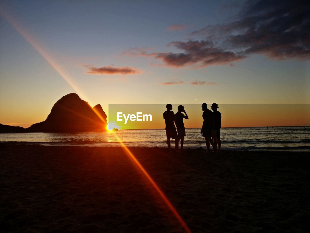 Silhouette people on beach against sky during sunset